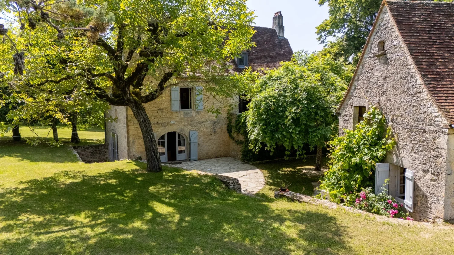 Stone house with blue shutters under trees